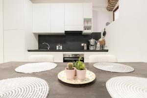 サロにあるC-Apartment Lake Gardaの白いキャビネットと鉢植えのテーブル付きのキッチン