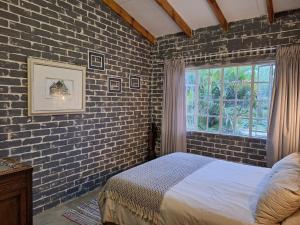 a bedroom with a brick wall with a bed and a window at Numbi Hills Self-Catering in Hazyview +59 photos