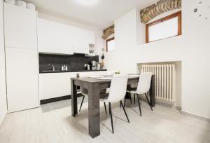 a kitchen with a wooden table and white chairs at C-Apartment Lake Garda in Salò