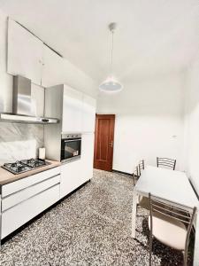 a kitchen with white cabinets and a table and chairs at A due passi da Brignole in Genoa