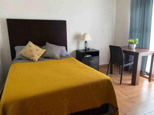 a bedroom with a yellow bed with a desk and a chair at Confortable Apartmento in Guanajuato