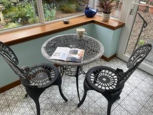 a table with two chairs and a table with a book at Peaceful Getaway In Peebles in Peebles