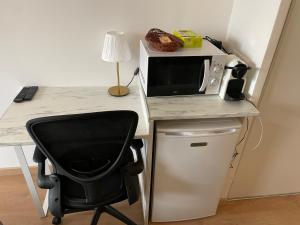 a desk with a microwave and a black chair at Exclusive Private Apartment by Warilco - Pleyel 25 m2 - À 1 minute de la station métro Carrefour Pleyel in Saint-Denis
