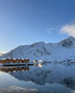 un lodge en un lago con montañas cubiertas de nieve en Charming waterfront cabin in Ballstad, Lofoten en Ballstad