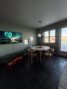comedor con mesa, sillas y ventanas en Charming waterfront cabin in Ballstad, Lofoten en Ballstad