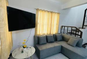 ein Wohnzimmer mit einem Sofa und einem Flachbild-TV in der Unterkunft Camella Mabini Cabanatuan in Cabanatuan