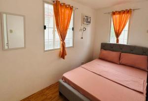 a bedroom with an orange bed and two windows at Camella Mabini Cabanatuan in Cabanatuan