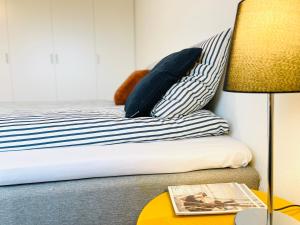 łóżko z poduszką w paski oraz stół z lampką w obiekcie Scandinavian Apartment Hotel - Torsted - 2 room apartment w mieście Horsens