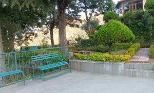 a blue bench in a park with trees and bushes at Himalayas Youth Hostel Kempty Mussoorie in Mussoorie