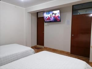 a bedroom with two beds and a flat screen tv at Hostal Tulipán Rojo in Lambayeque