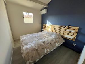 een slaapkamer met een bed en een blauwe muur bij Maison avec jardin in Le Grau-du-Roi