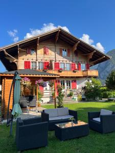 a large wooden house with chairs and an umbrella at Chalet Maria Interlaken in Interlaken
