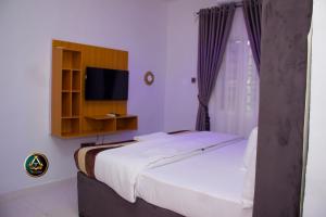 una camera con un grande letto e una televisione di TRILLIONS HOTEL AND APARTMENT a Benin City