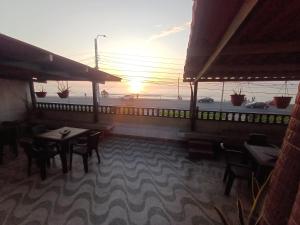 um restaurante com mesas e cadeiras com o pôr-do-sol ao fundo em Julia house em Huanchaco