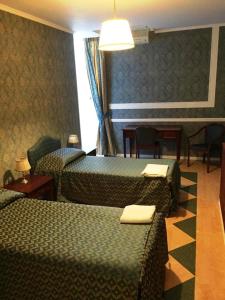 コゼンツァにあるHotel Excelsiorのベッド2台、テーブルと椅子が備わるホテルルームです。