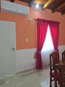 Habitación con cortinas rojas y ventana en Cabañas Maciel en San Rafael
