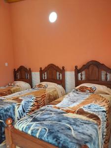 3 camas en una habitación con paredes de color naranja en Cabañas Maciel en San Rafael