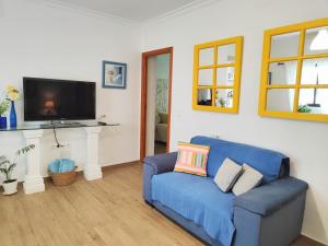 a living room with a blue couch and a tv at Céntrico apartamento con terraza y WIFI in Ronda