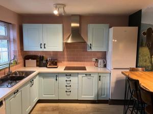 a kitchen with white cabinets and a white refrigerator at The Whimsy 2 bedroom cottage in National Forest, private parking & garden in Blackfordby
