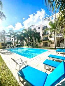 einen Pool mit blauen Liegestühlen neben einem Gebäude in der Unterkunft Departamento Blue Vacacional in Playa del Carmen