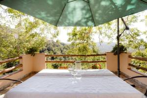 a table with wine glasses and an umbrella on a balcony at Agrifoglio B&B con giardino in Aritzo