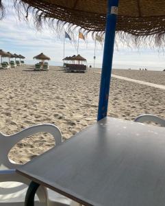 einen Tisch am Strand mit Stühlen und Sonnenschirmen in der Unterkunft Mar y sol in Benalmádena