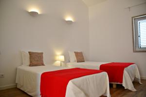 1 dormitorio con 2 camas con sábanas rojas en Quinta da Caldeireira, en Rosmaninhal