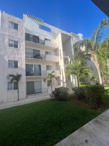 a large white building with palm trees in front of it at Departamento Blue Vacacional in Playa del Carmen