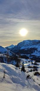Sonnleitn AlpinWell Appartment (Ski in&out + Wellness) في هيرماغور: جبل مغطى بالثلج مع الشمس في المسافة
