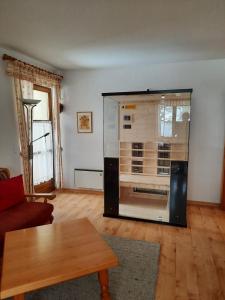 Sonnleitn AlpinWell Appartment (Ski in&out + Wellness) في هيرماغور: وجود صندوق زجاجي كبير في غرفة المعيشة مع طاولة