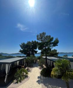 a building with a pathway and trees and the sun at Dalmaris camp - prestige mobile homes Biograd na Moru in Biograd na Moru