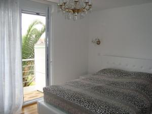 a bedroom with a bed and a window with a chandelier at Natalie Apartments in Tivat