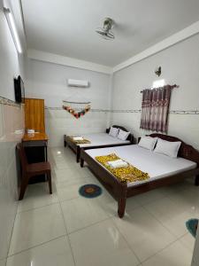 a room with two beds and a table and a chair at Nhà Nghỉ HOA LÝ in Chau Doc