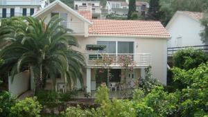 a white house with a palm tree in front of it at Natalie Apartments in Tivat