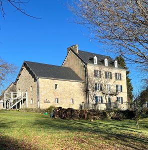 a large brick building on a grass field at Chez Jallot in Vidaillat