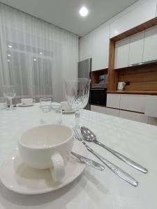 a white table with a plate and glasses on it at 2-х комнатная квартира in Semey