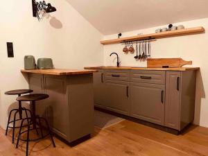 eine Küche mit einer Spüle und einer Theke mit Hockern in der Unterkunft stilvolles und komfortables Chalet mit Weitblick in Ebenfeld