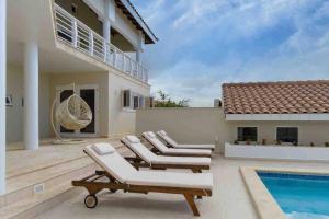 a patio with lounge chairs and a swimming pool at NewVilla-Coral Estate-WalktoBeach-Private Pool-up to 16 Guests SeaView in Willibrordus