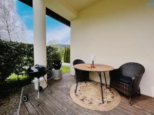 a patio with a table and chairs on a deck at Gemütliches Seeapartment am Berg in Arrach