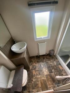 a bathroom with a toilet and a sink and a window at Orchid meadows retreat in Ashington
