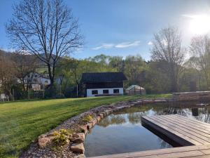 a pond in front of a building with a wooden bridge at Appartement am Teich in Hainfeld