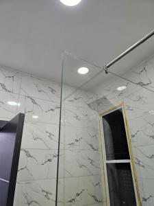 baño con paredes de mármol blanco y espejo en Hencapservices 002HPS., en Agege