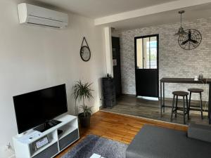 een woonkamer met een flatscreen-tv en een tafel bij Appartement proche Grenoble centre et campus in Saint-Martin-dʼHères