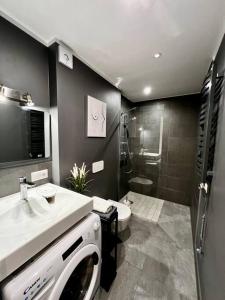 een badkamer met een wastafel, een toilet en een douche bij Seashell Albatross Boutique Apartment in Ķesterciems
