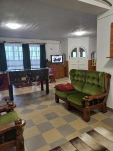 a living room with a green couch and a piano at Evita Vendégház in Sajókápolna