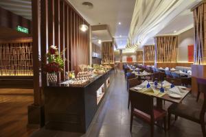 um restaurante com mesas e cadeiras e um bar em Ramee Rose Hotel em Manama