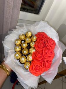 une personne détenant un bouquet de roses et de chocolats en forme de cœur dans l'établissement Suite romantique avec jaccuzy à la gare de Montpellier, à Montpellier