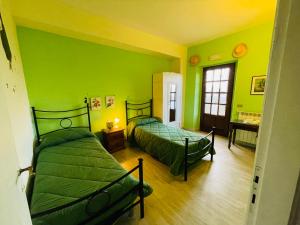 twee bedden in een kamer met groene muren bij Maremma Nel Tufo in Pitigliano
