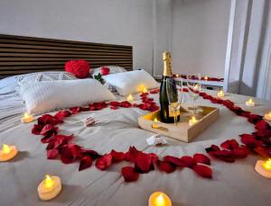 Una cama con rosas rojas y velas y una botella de champán. en Logement complet Dijon Centre jusqu'à 6 couchages, en Dijon
