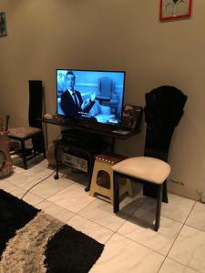 uma sala de estar com uma televisão de ecrã plano e uma cadeira em Room in Guest room - Logerthine Cambridge Suriname em Paramaribo